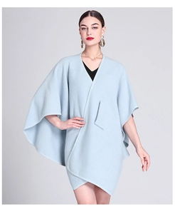 Detail of light blue knit poncho cardigan showing the relaxed fit and elegant drape