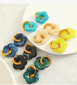 Macro shot of colorful camellia flower earrings with marble texture and gold metal rings