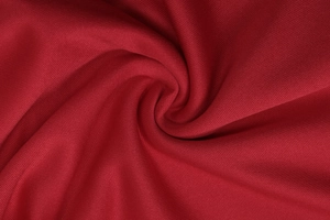 Macro texture detail of dark red polyester blend fabric with elegant spiral pleat patterns