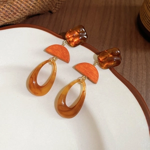 Detail of amber resin drop earrings with geometric wood texture and golden metal links