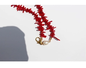 Detail of red coral-style stone necklace with pearl and gold heart-shaped lobster clasp