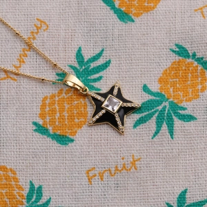 Detail of gold star pendant necklace with black enamel and sparkling zircon accents