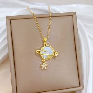 Macro detail of gold planet pendant with stars and moon on a white silk background