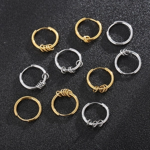 Detail of minimalist gold and silver stainless steel hoop earrings on black surface