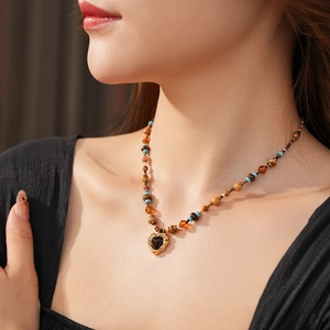 Close-up of Bohemian beaded necklace with vintage black heart pendant on a model
