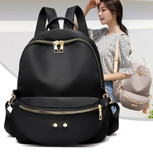 Detail of waterproof nylon backpack featuring gold zippers and front pocket with model view