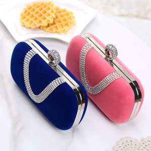 Close-up of velvet evening clutch bags with sparkling rhinestone trim on white marble