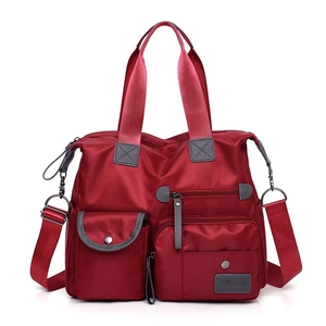 Detail view of durable red Oxford cloth handbag featuring multiple pockets and sturdy handles