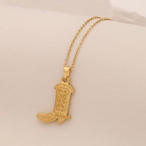 Vue macro d'un pendentif botte doré avec textures cœur sur un support en papier beige