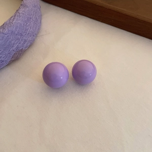 Macro shot of purple spherical bead earrings on soft fabric with textured background