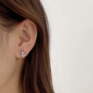 Detailed close-up of a silver knot earrings worn by a model in a minimalist style