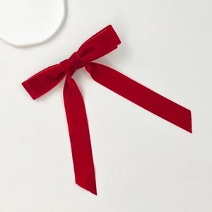 Detailed texture of a vintage burgundy velvet bow hair clip with elegant long streamers
