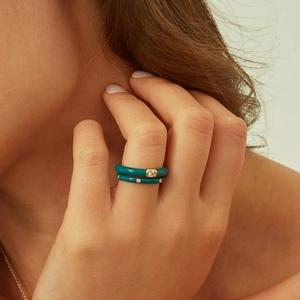 Set of teal enamel rings with gold edges and zircon stones worn on finger