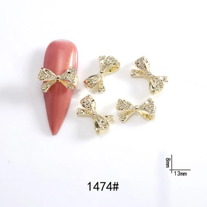 Detail showing a golden metal bow nail art charm with size 13mm by 8mm for manicures