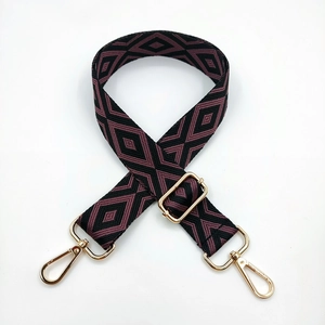 Detail view of adjustable embroidered bag strap with purple diamond patterns and gold hooks