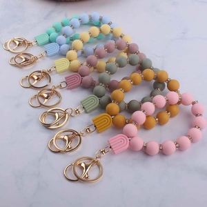 Detail of colorful silicone rainbow keychains with beads on marble surface