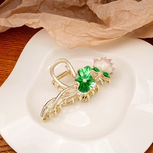 Detailed view of a gold hair claw clip featuring a 3D lotus flower and green leaf