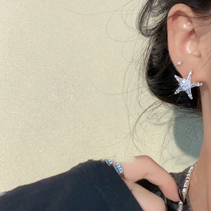 Detailed close-up of a silver starfish stud earring featuring zircon inlay on a model