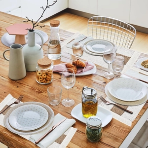 Nordic woven linen placemat set with ceramic plates and glassware on a wooden table