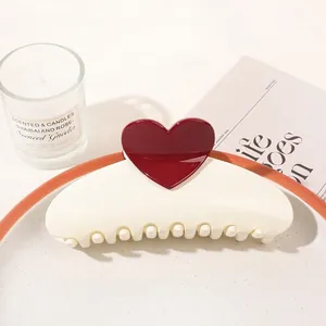 Detail shot of a cream-colored hair claw clip with red heart detail on a decorative tray