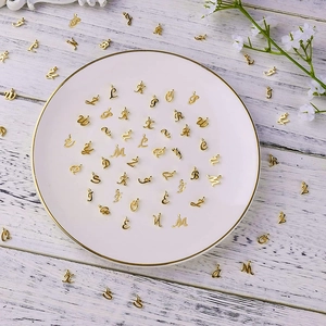 Golden alphabet charms displayed in a white ceramic dish on a rustic wooden tabletop