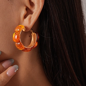 Macro view of tortoiseshell resin hoop earring with gold metal setting on a model