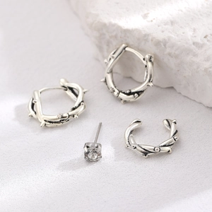 Detail of gothic silver earrings featuring thorn vine cuffs and a sparkling stud