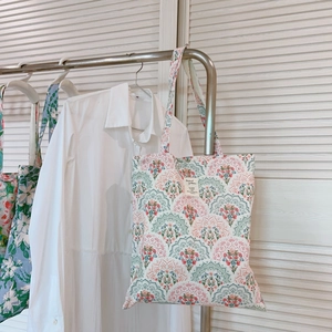 Detail of floral mandala canvas tote bag featuring a white woven brand label and artistic print