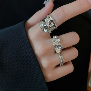 Detailed view of silver irregular lava texture rings styled on a black blazer background