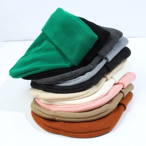 Vertical stack of colorful knit beanies showing ribbed texture and warm winter fabric