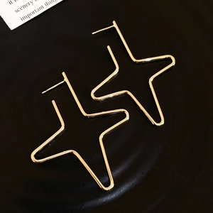 Detail of minimalist gold hollow star earrings on a matte black textured background