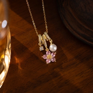 Detail of gold flower necklace with pink crystals, pearl pendant and micro-set diamond