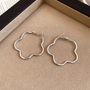 Detailed 45-degree macro view of silver wavy geometric hoop earrings on a velvet tray