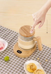 Detail of 400ml automatic glass stirring mug with wood grain base on a wooden table