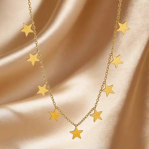 Close-up of gold stainless steel star necklace on luxurious champagne silk background