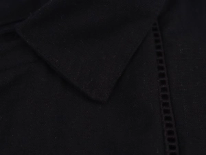 Macro detail of the black linen fabric texture and V-neck hollow stitching craftsmanship