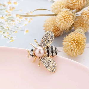 Detailed close-up of a golden bee brooch featuring pink pearls and sparkling rhinestones