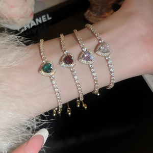 Detail of adjustable heart bracelet with vibrant emerald and ruby colored gemstones