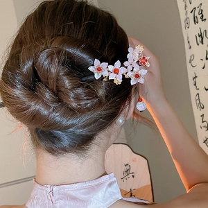 Detail of a floral hair stick with pink and red tassels on an elegant updo hairstyle