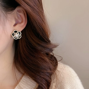 Detail of vintage flower stud earring with black enamel and a pearl on model ear