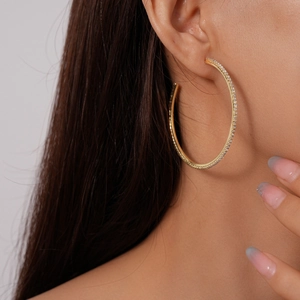 Close-up of a model wearing large gold-plated hoop earrings with pavé-set crystals