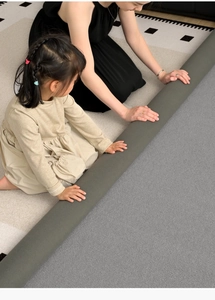 Washable gray chenille rug being spread out by a family on a wooden floor in a living room