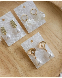 Detailed view of three gold earring styles with white pearls on display cards