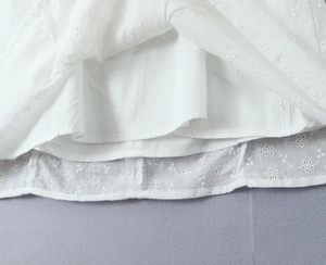 Detailed close-up of white dress hem featuring delicate floral embroidery and smooth lining
