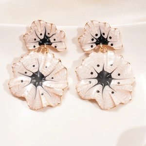 Detailed close-up of ginkgo flower earrings with white enamel and golden star accents