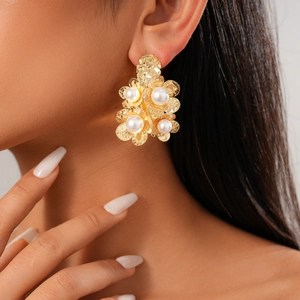 Detail of 18K gold plated flower earrings with pearl centers worn by a model