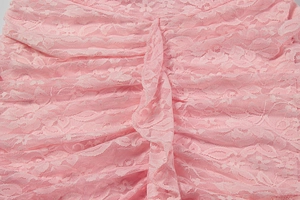 Close-up of pink lace fabric with delicate floral patterns and ruffled textures
