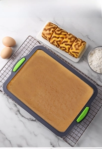 Close-up of rectangular silicone brownie mold with green non-slip handles on marble