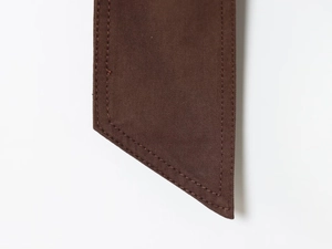 Detailed close-up of dark brown twill fabric with precise parallel double stitching craft