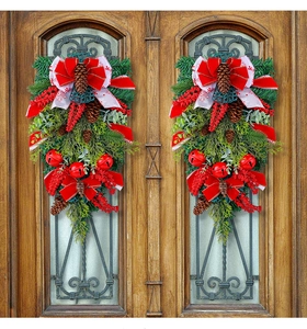 Detailed close-up of Christmas door swags with red bows and pine cones on wooden doors
